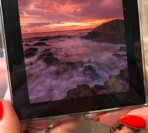 Glass photo coaster with a sunset seascape print held in a hand