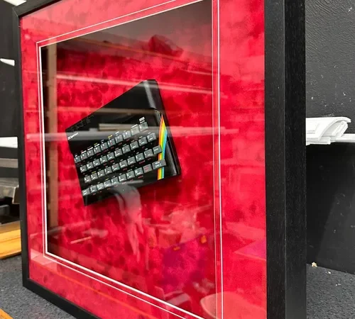 Framed ZX Spectrum computer behind glass in a deep box frame with a red mount