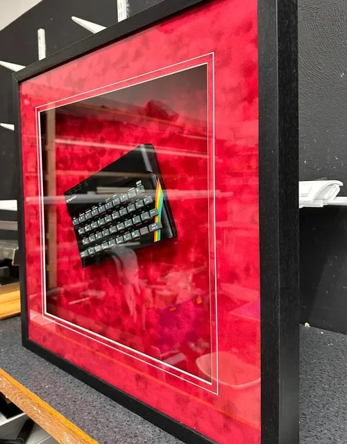 Framed ZX Spectrum computer behind glass in a deep box frame with a red mount