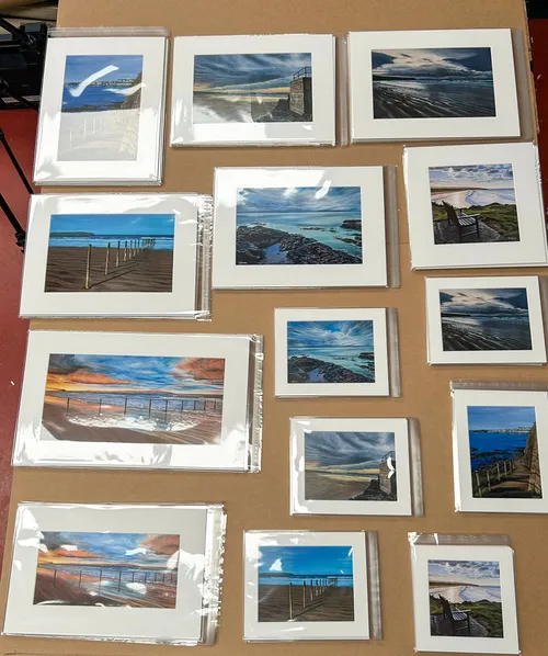 Collection of mounted landscape photographs laid out on a studio table